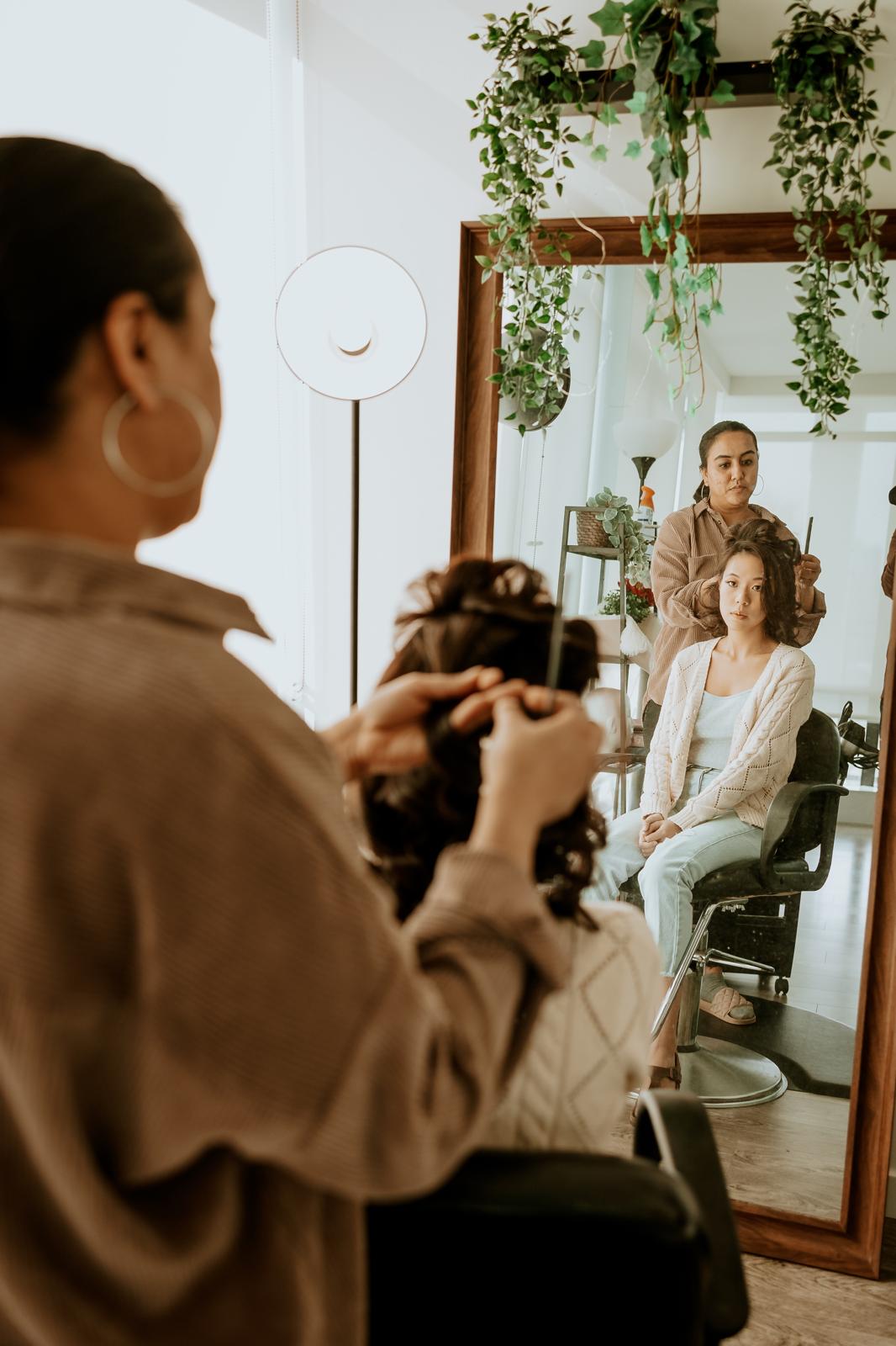 Dwija Patel styling a client's hair in the studio mirror